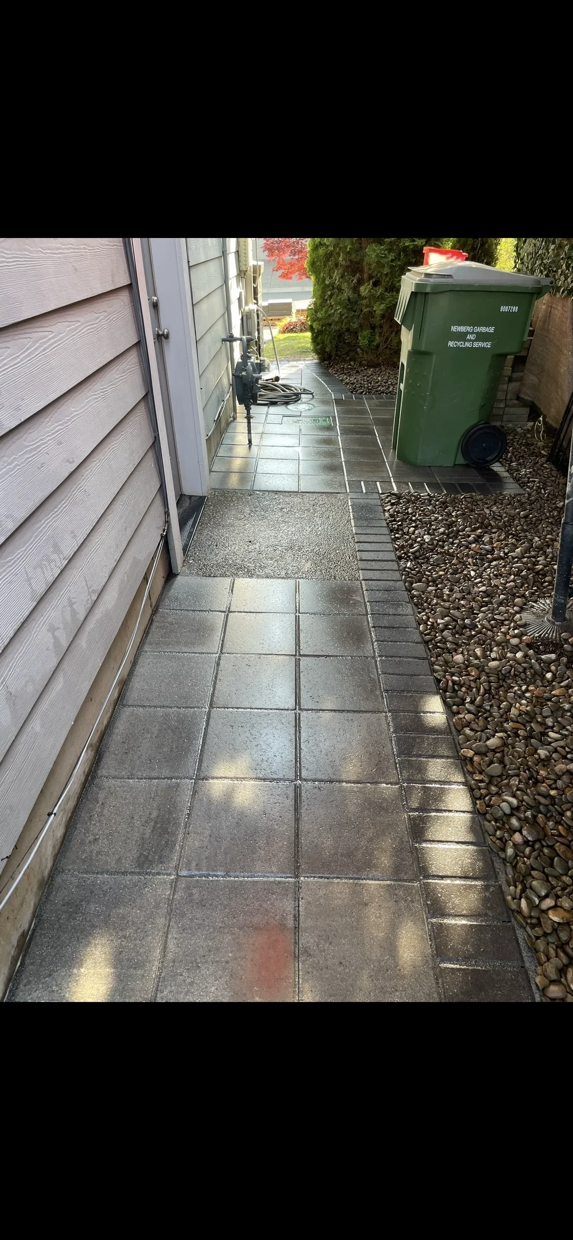 Concrete paver walkway with river rock borders and edging in residential side yard