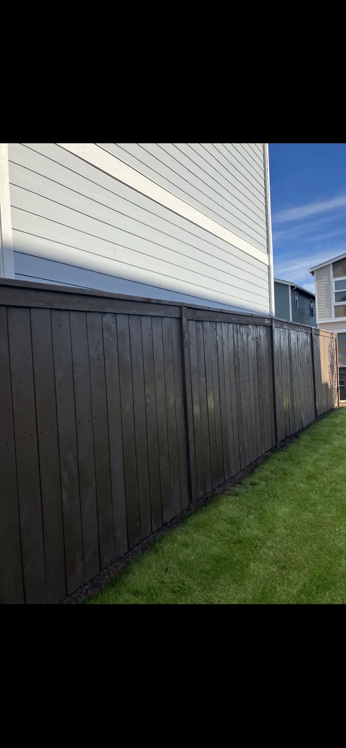 Black vinyl privacy fence with vertical boards installed along residential property line