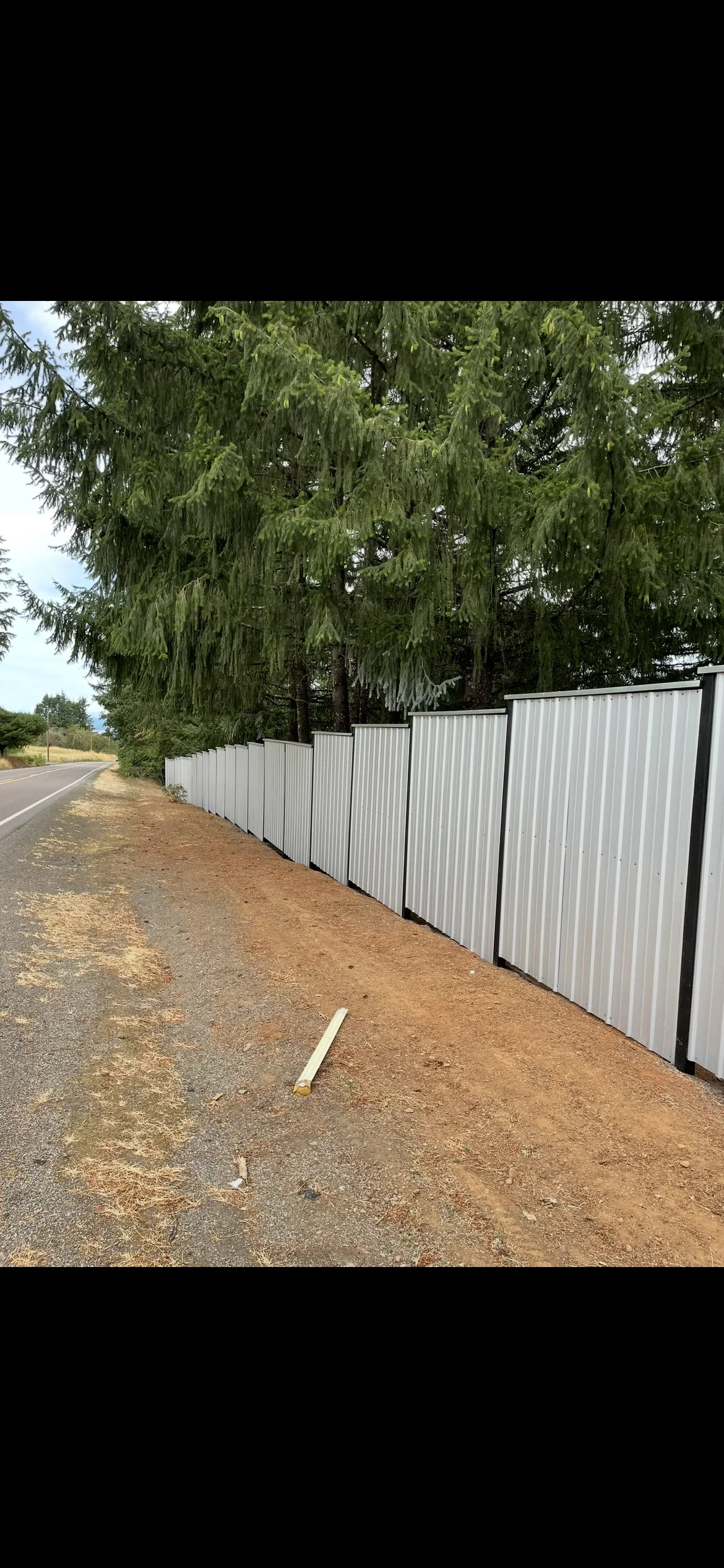White corrugated metal fence with black steel posts installed along property line