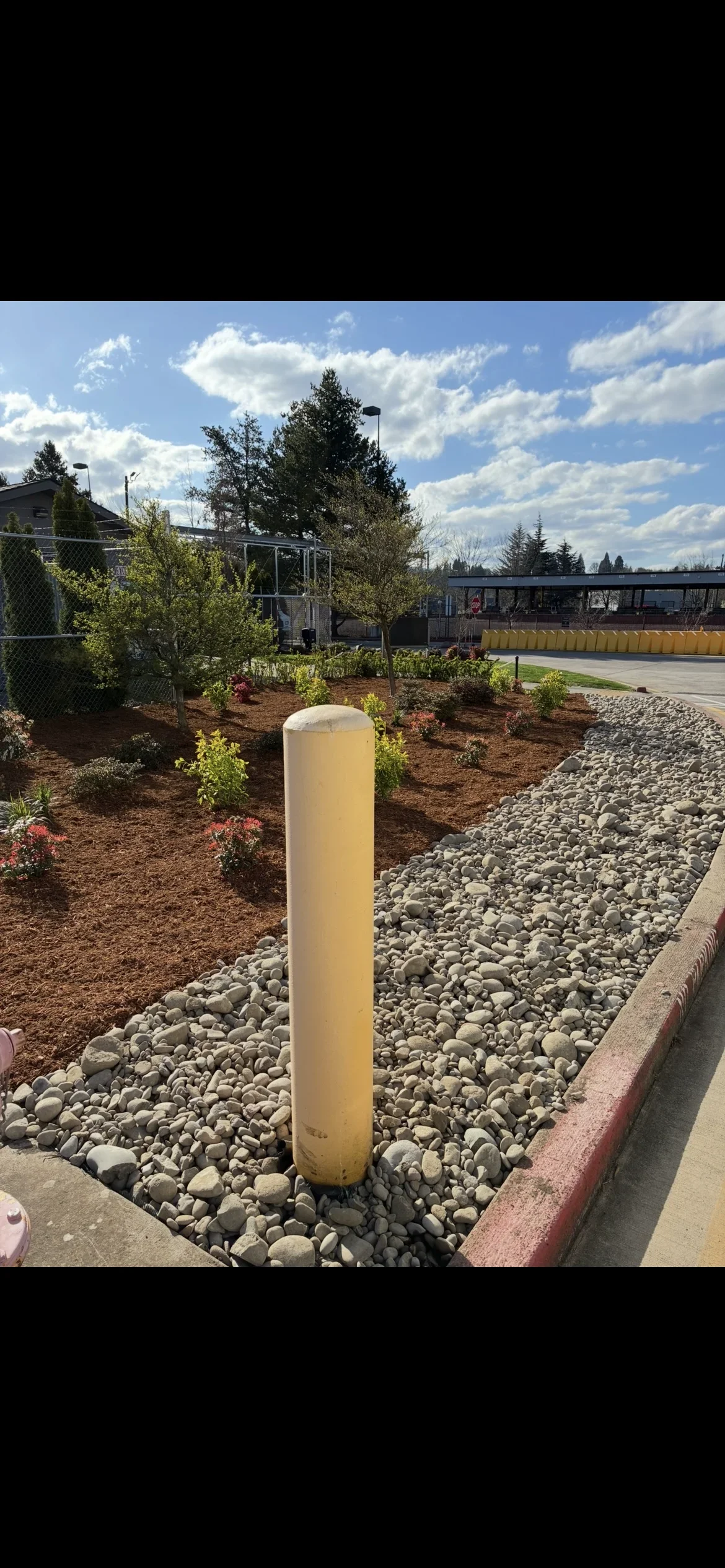 Yellow bollard in river rock with new plantings, mulch beds, and landscape edging