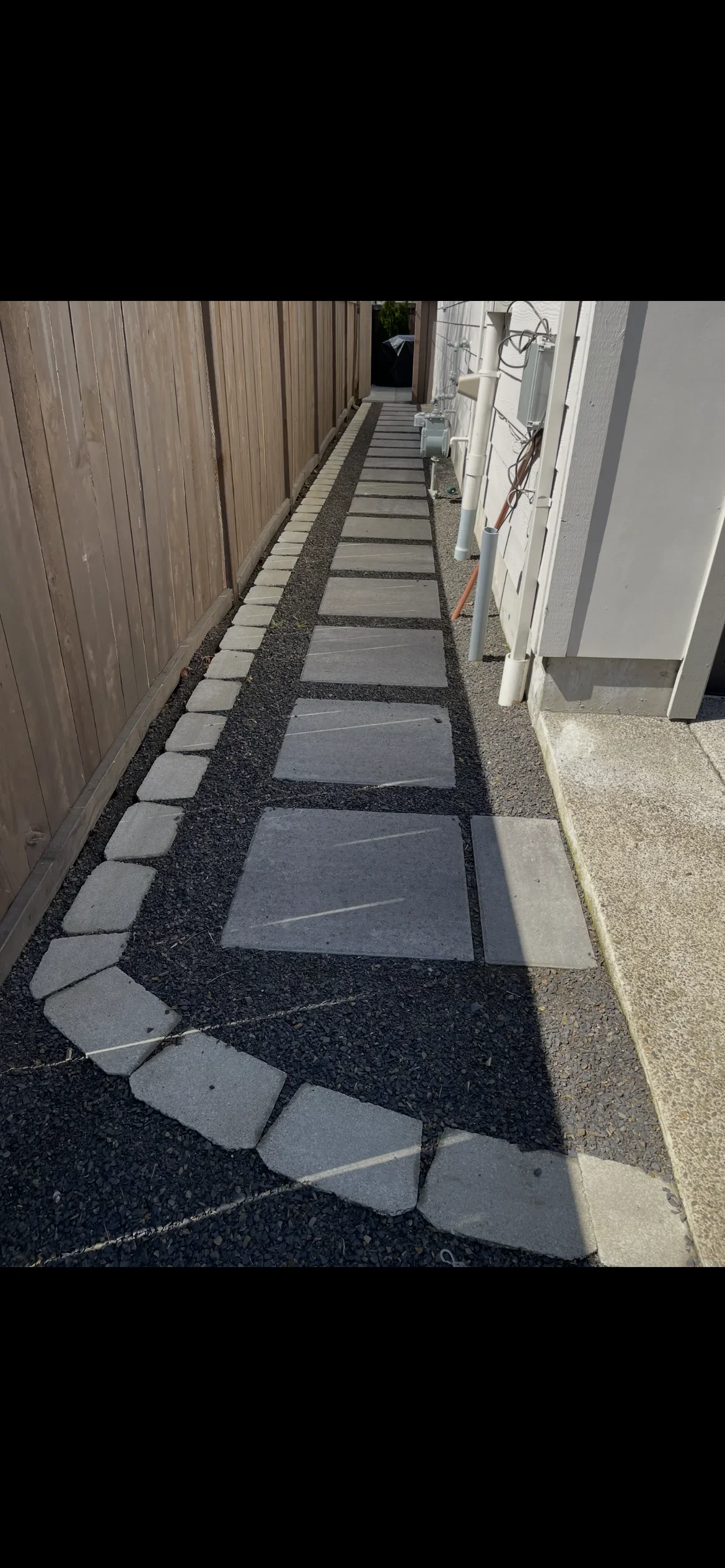 Stepping stone pathway with gray pavers and dark gravel in narrow side yard
