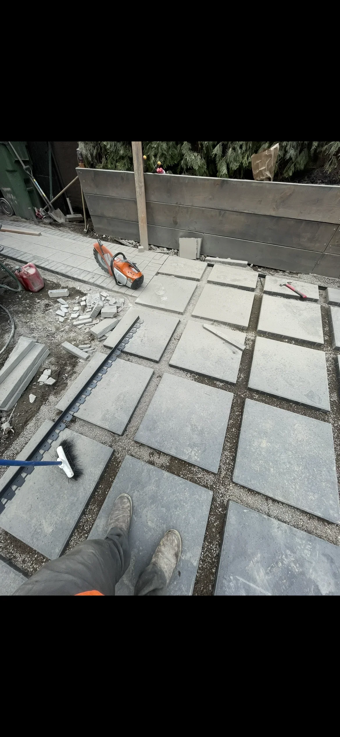 Concrete pavers laid in grid pattern with gravel joints and metal edging during installation
